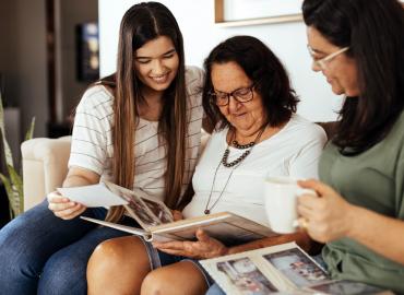 Three women looking at a photo album.